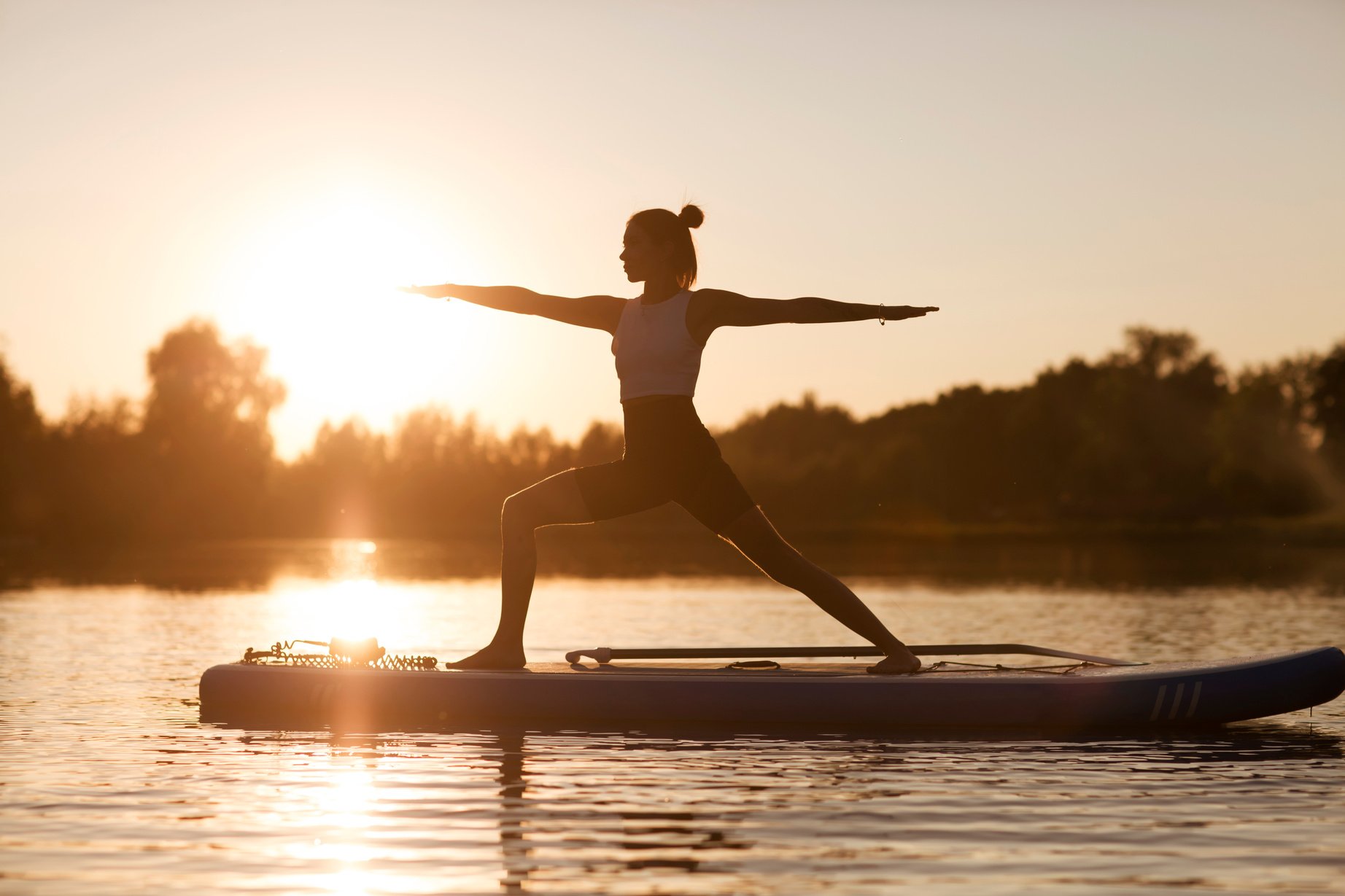 woman doing yoga on sup board at sunset. outdoor summer activity. Sup yoga.  Social Distancing. copy space. Mental Health